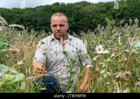 Farmer in a pollinator strip of flowers on the edge of his field which is grown to encourage insects and wildlife. Co. Durham, UK. Stock Photo