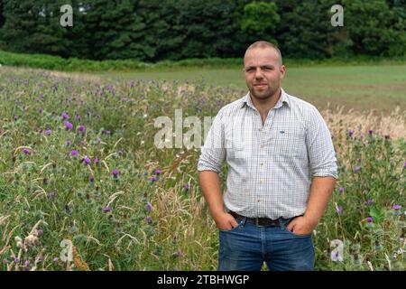 Farmer in a pollinator strip of flowers on the edge of his field which is grown to encourage insects and wildlife. Co. Durham, UK. Stock Photo