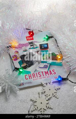 A 2017 Argos Christmas catalogue (gift guide). Photographed on a neutral background with coloured Christmas lights, decorations and luxury tinsel Stock Photo