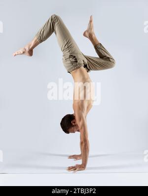 athletic man practicing yoga on a white mat with a white background Stock Photo