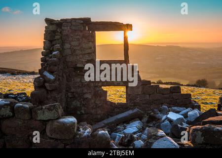 A setting sun beyond a ruined farmhouse Stock Photo