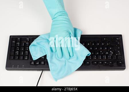 Cleaning computer keyboard in office with a wet wipe rag, dusty and dirty electronic, housework Stock Photo