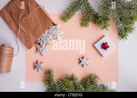 On peach fuzz isolated background lie craft bag with silver gingerbread cookies in shape of snowflake for Christmas. Top view of still life with green Stock Photo