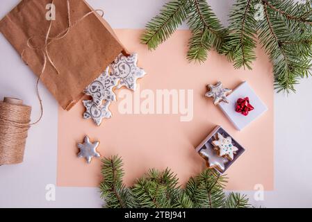 On peach fuzz isolated background lie craft bag with silver gingerbread cookies in shape of snowflake for Christmas. Top view of still life with green Stock Photo