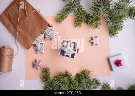 On peach fuzz isolated background lie craft bag with silver gingerbread cookies in shape of snowflake for Christmas. Top view of still life with green Stock Photo