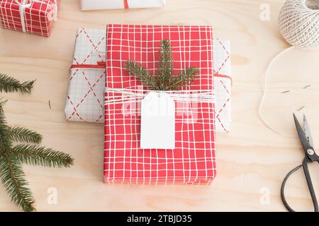 Red and white christmas gifts surrounded with pine cones, leaves and twine on a wooden table. Stock Photo