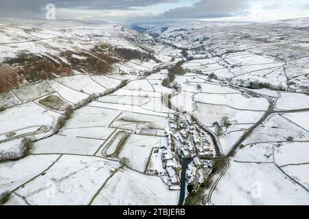 Looking down a snow covered Swaledale in early winter, with the hamlet of Thwaite in the foreground and the River Swale meandering down the dale. York Stock Photo