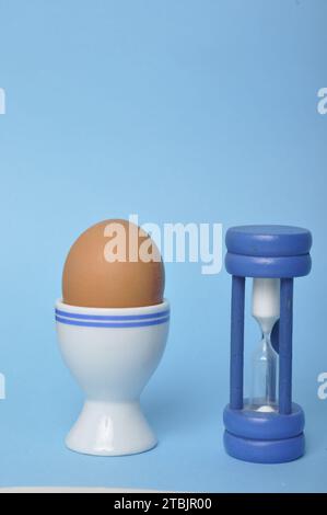 Boiled egg and hourglass on a blue background Stock Photo