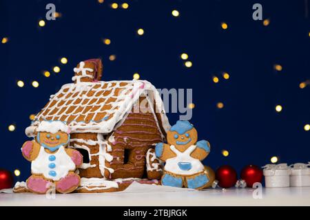 Christmas gingerbread in the shape of men is decorated with colorful sugar icing and a cookie house. Stock Photo