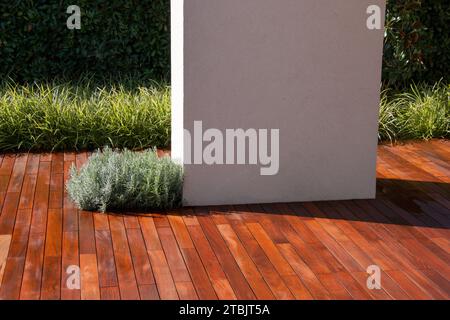 White concrete pillar on hardwood terrace floor patio with evergreen grass garden Stock Photo