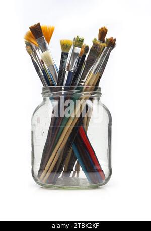 Set of used paintbrushes in glass jar isolated on white background Stock Photo