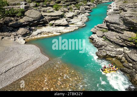 White water rafting.  Adventure and sport. A yellow raft floating among the rocks on the crystal clear, blue-green water. Drone view. Stock Photo