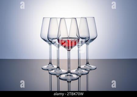 Glass of red wine in front of other empty glasses on white background Stock Photo
