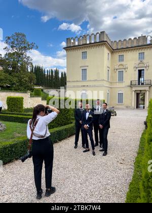 Rome, Italy - 09 august 2023: Photographer girl shoots the groom with his friends in the garden of an old mansion Stock Photo