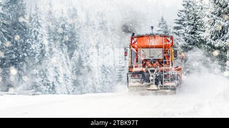 Snow plow on highway salting road . Orange truck deicing street. Maintenance winter gritter vehicle wide panorama or banner. Stock Photo