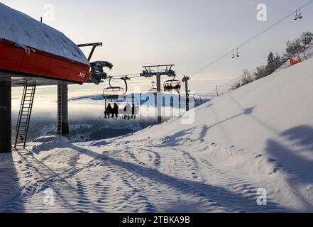 A group of people enjoying a ski lift ride, skiing down a snowy hill Stock Photo