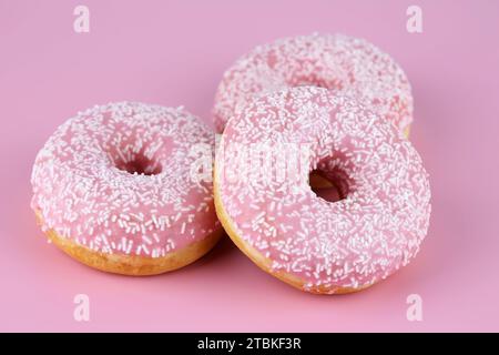 Three fresh donuts on pink background. Stock Photo