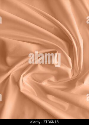 Peach fuzz is the color of the year 2024. Silk fabric folded with beautiful curves with shadows, top view Stock Photo