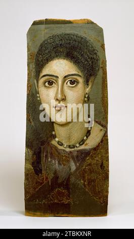 Panel Portrait of a Woman, 2nd century CE. In Roman Egypt (30 BCE-324 CE), artists adapted naturalistic painting styles to the ancient custom of making portrait masks for mummies. The portraits were often painted while the subject was in the prime of life and were hung in the home until the person's death. This practice continued in northern Egypt well into the Early Byzantine period. Hairstyles can be used to date female portrait masks. Here, the braids wound over the top of the head place the mask close to the period of the Roman emperor Trajan (AD 98-117). The painting of a portrait was an Stock Photo