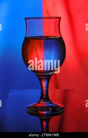a wine glass filled with water on a two-color background creates light diffraction and reflection Stock Photo