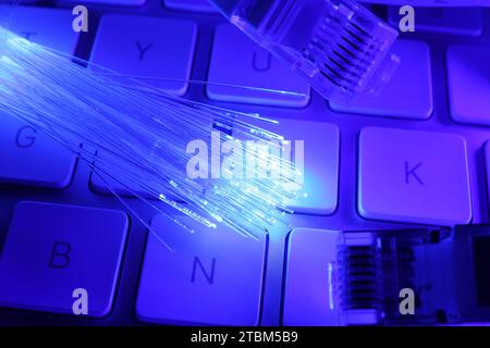 Optical fiber strands transmitting color light and modular connectors on computer keyboard, closeup Stock Photo