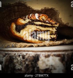 Fresh poppy seed roll on natural linen napkin on rustic wooden background Stock Photo