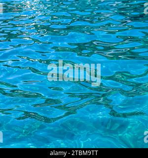 Turquoise sea waves in sunshine glow as surface background. Summer holidays and coastal nature concept Stock Photo