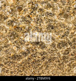 A background of sand, small pebbles and flowing waves on the sea beach. Summer vacation and coastal nature concept Stock Photo