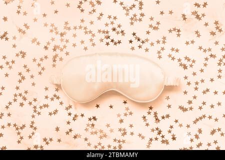 Color of the year 2024 Peach Fuzz. Satin eye sleeping mask and stars background. Sweet dreams Stock Photo