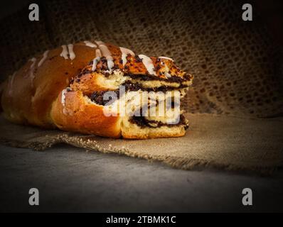 Fresh poppy seed roll on natural linen napkin on rustic wooden background Stock Photo