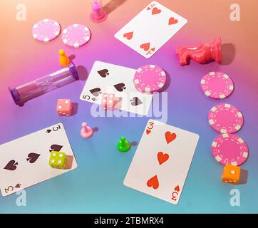Game Night Top view Scene with Poker Chips, Playing Cards, Chess Pieces, Dice, Gaming Sand Timers and Board game Pawns on a Pastel Pink & Blue Backgro Stock Photo