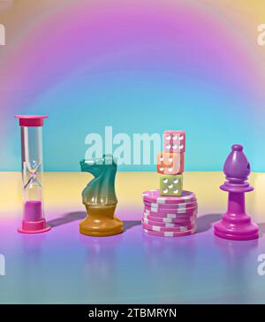 A Game Night Scene with a Pink Sand Timer, Green Knight Chess Piece, Pink Stacked Poker Chips, Three Dice and a Bishop Chess Piece Stock Photo