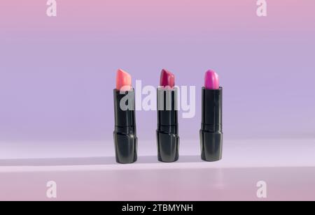 Three Tubes of Red and Pink Beauty Lipstick Cosmetics on a Purple Background Stock Photo