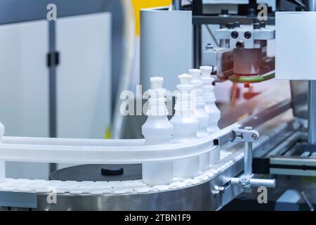 Moving polypropylene white bottles on conveyor belt of automatic liquid filling machine Stock Photo