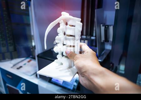 hand with 3d printed human spine in 3d printer. Stock Photo