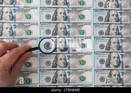 Counterfeiter forges banknotes. Fake concept. Fake money American dollars, magnifier. view money under a magnifying glass. watermark, water mark. sear Stock Photo