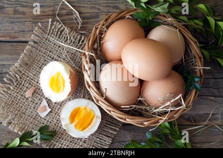 Eggs in basket decorated with boxwood on wooden boards, easter concept Stock Photo