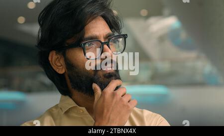 Indian pensive man in eyeglasses thinking. Close up thoughtful male face look distance indoors pondering business idea searching problem solution Stock Photo