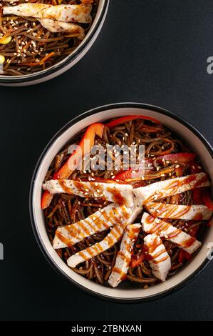 Asian buckwheat noodles with vegetables, sauce and chicken in a bowl Stock Photo