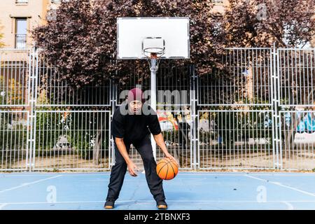 multiracial man playing with basketball on court Stock Photo