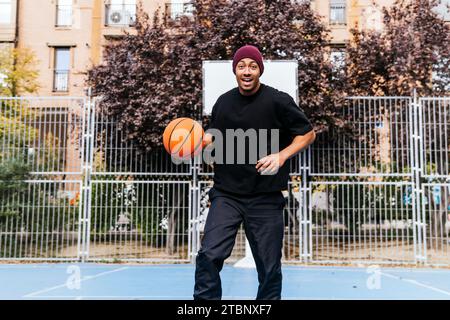 multiracial man playing with basketball on court Stock Photo