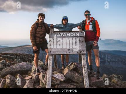 Three male friends stand at summit sign of Katahdin, Appalachian Trail Stock Photo