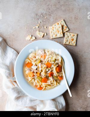 Top view chicken noodle soup in white bowl on beige background. Stock Photo