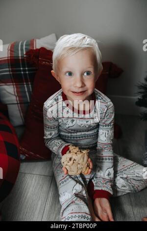 Boy happily eats cookie by tree Stock Photo