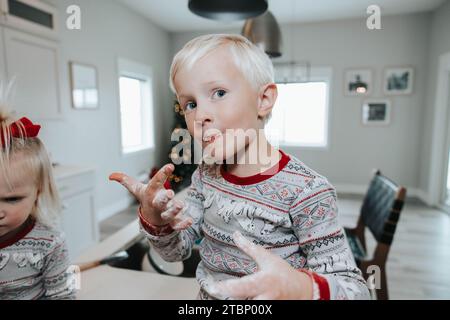 Boy helps bake Christmas cookies, floury hands Stock Photo