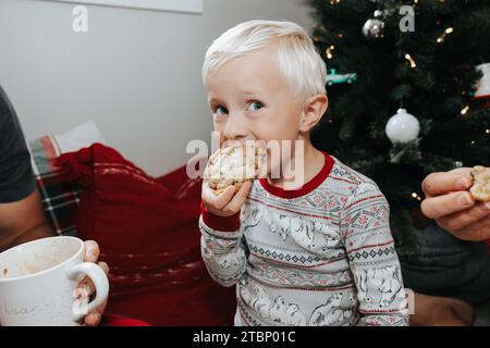 Boy happily eats cookie by tree Stock Photo