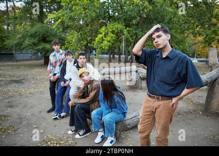 thoughtful young man standing in a group of friends in the park Stock Photo