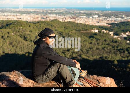 Middle-aged man contemplates the landscapes of the Garraf Natural Park while resting at the top of the mountain. Stock Photo