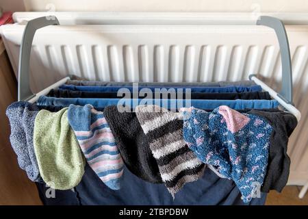 Laundry clothes drying on a rack attached to a home heating radiator. Stock Photo