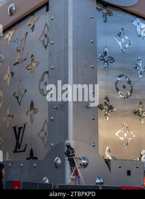 Paris, France - 12 06 2023: Champs-Elysees avenue. View of the detail of the facade of Louis Vuitton with christmas decoration and a worker on a stepl Stock Photo